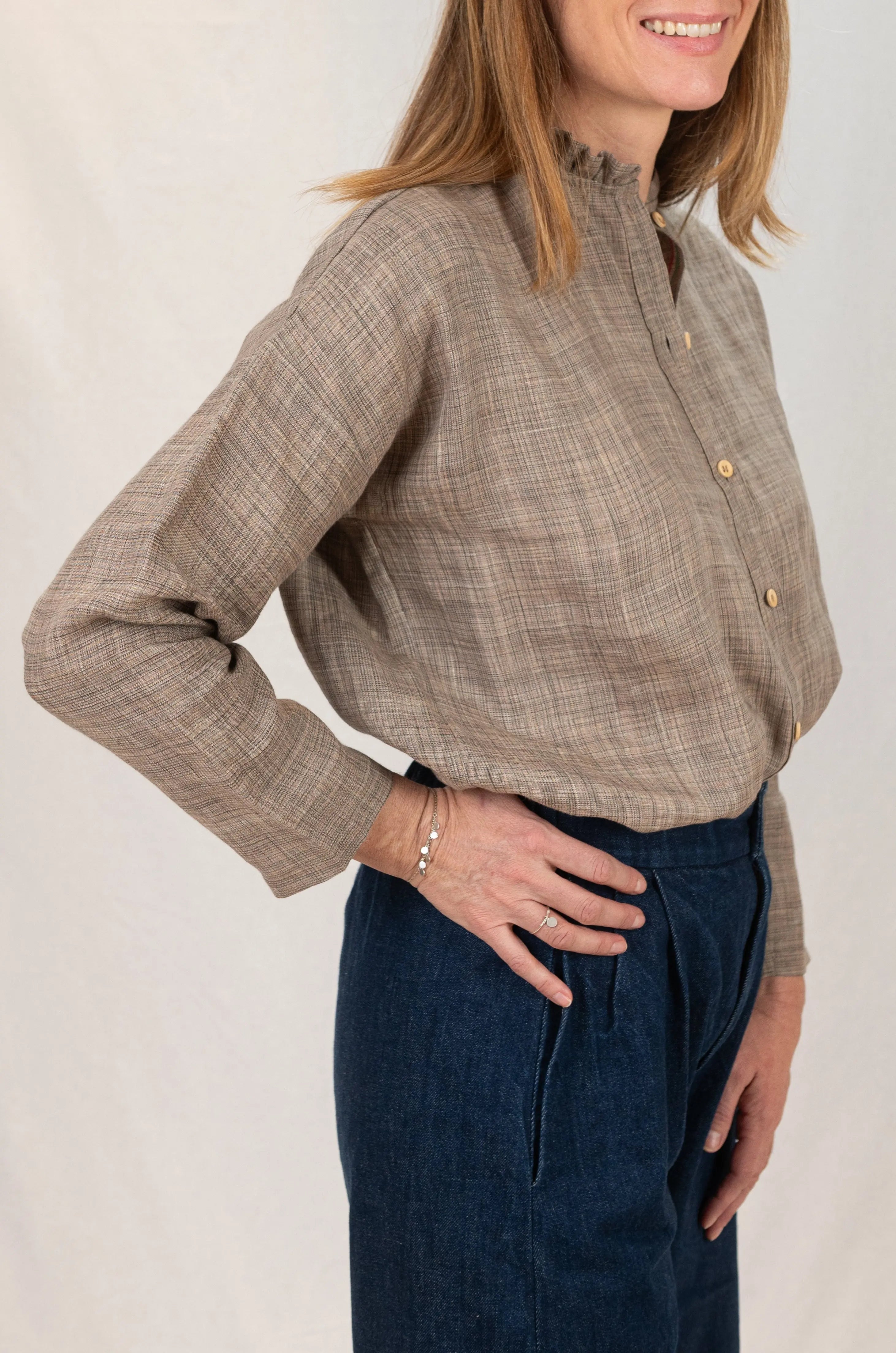 Chemise Narcisse à col froncé en lin couleur grège naturel, vue de profil, avec bouton en bois, portée avec un pantalon Sylène en denim, coupe Barrel Leg.