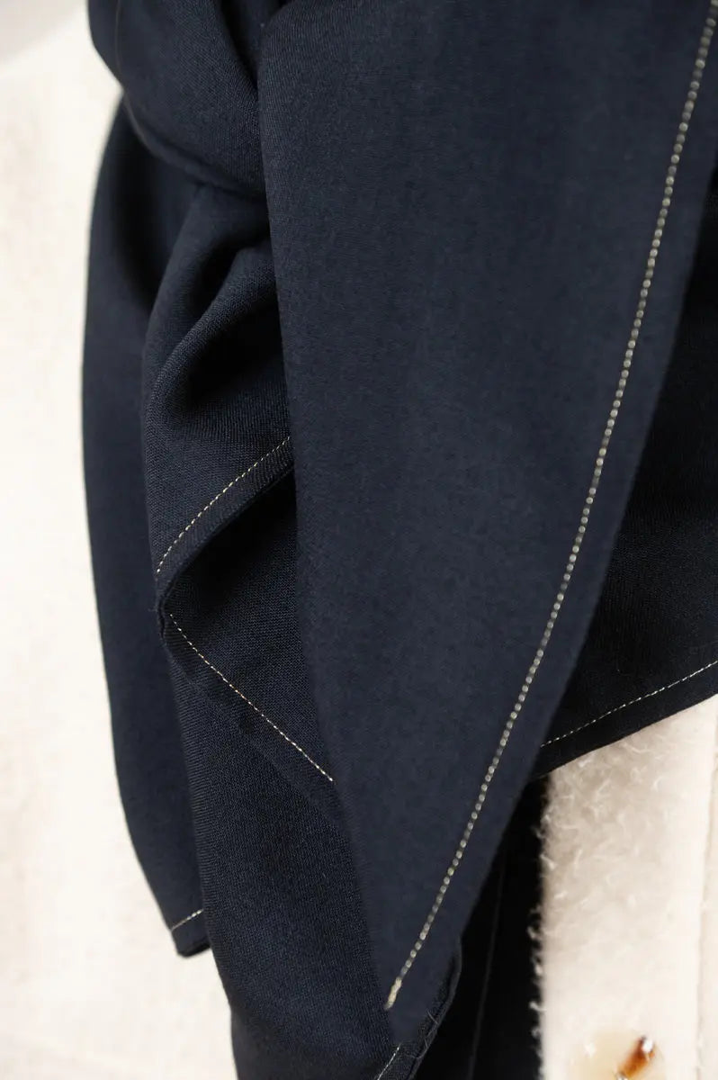 Écharpe triangle Airelle en étamine de laine bleu marine, détail de la couture dorée, portée avec le manteau Cévennes en drap de laine Casentino.