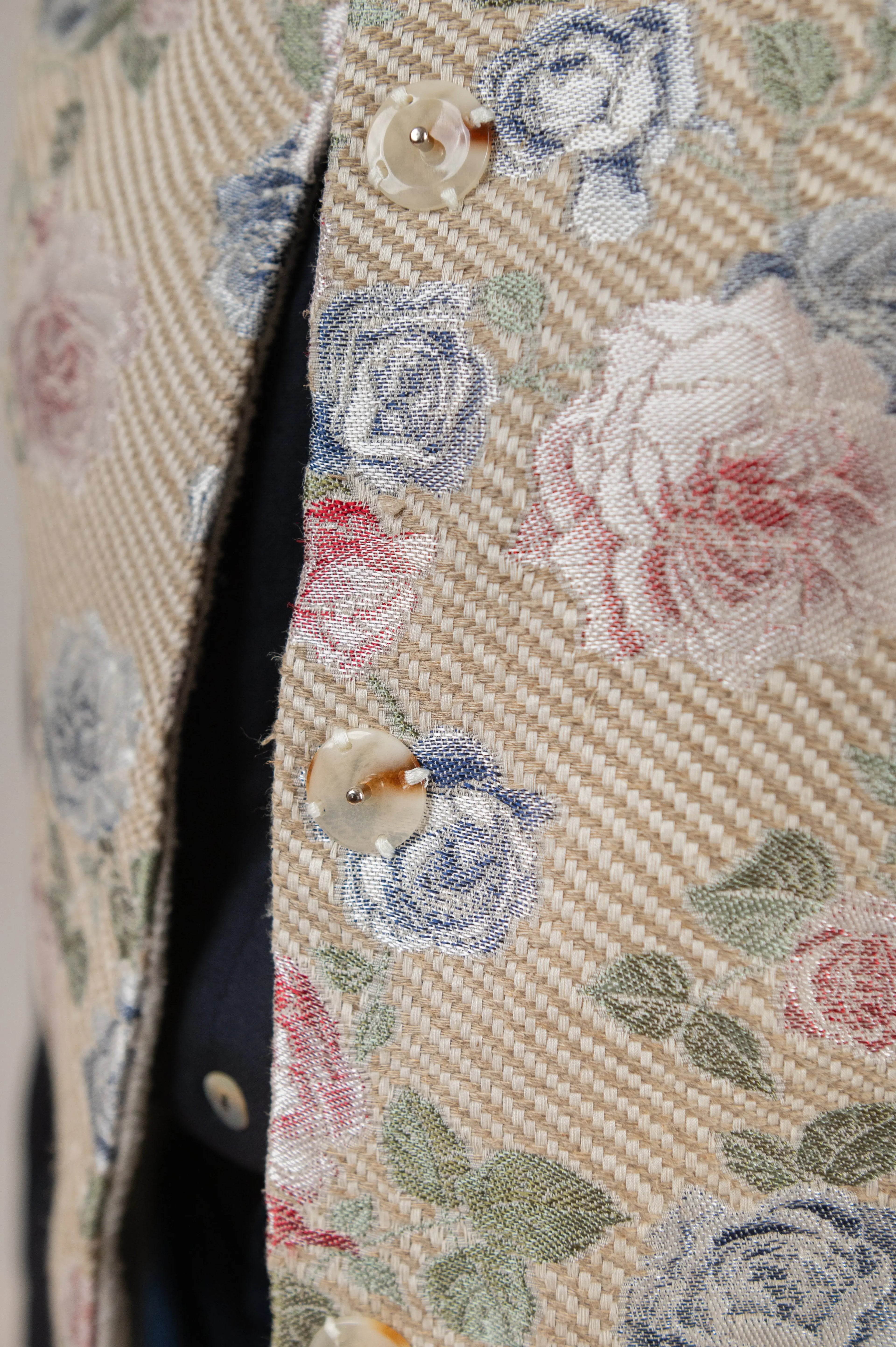 Gilet sans manches Ouessant réversible en jacquard fleuri, détail des boutons, porté sur une chemise Narcisse bleu marine en étamine de laine.