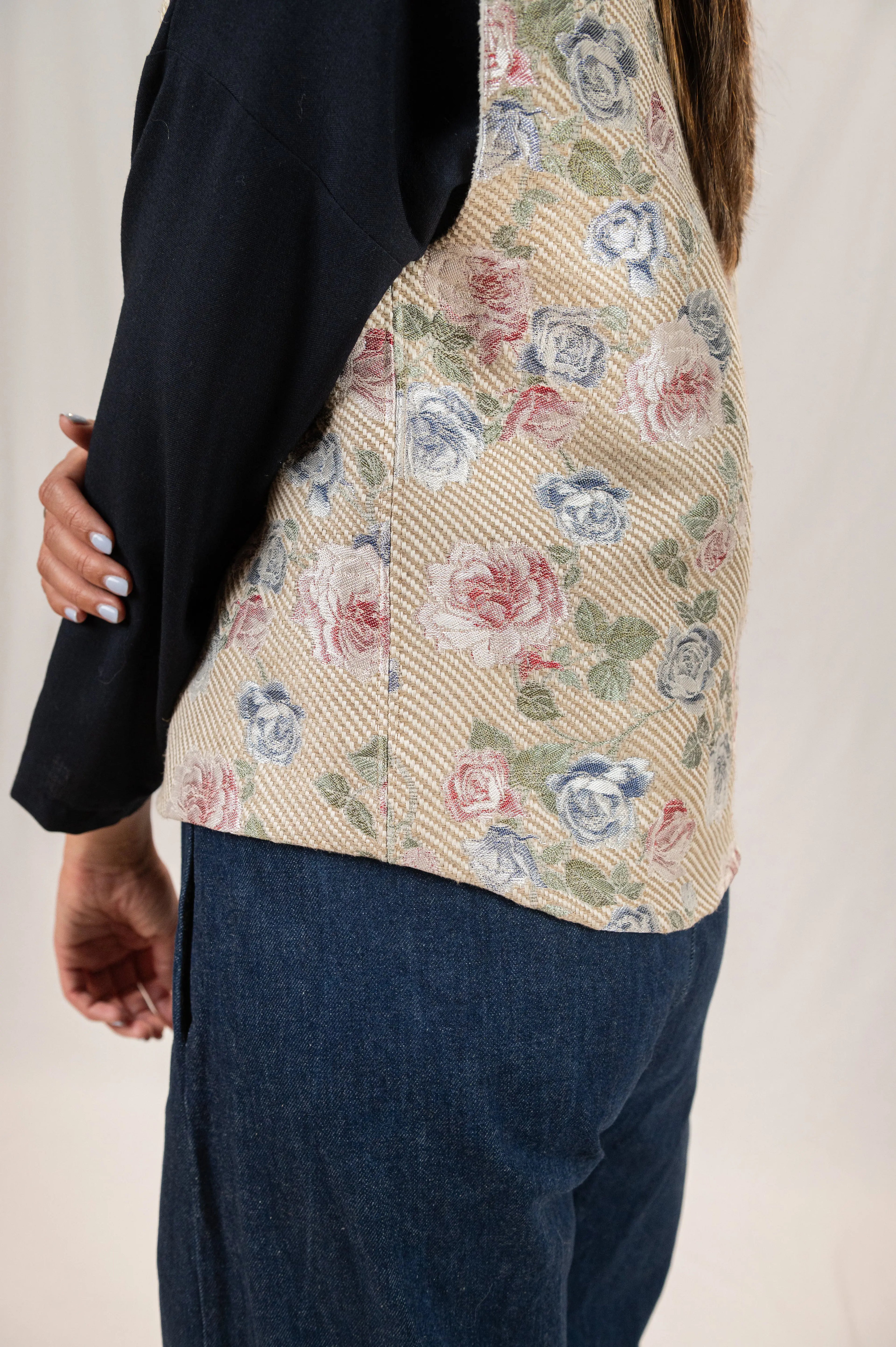 Gilet sans manches Ouessant réversible en jacquard fleuri, détail de la coupe dos recouvrant, porté sur une chemise Narcisse bleu marine en étamine de laine et un pantalon Sylène en denim bleu foncé.