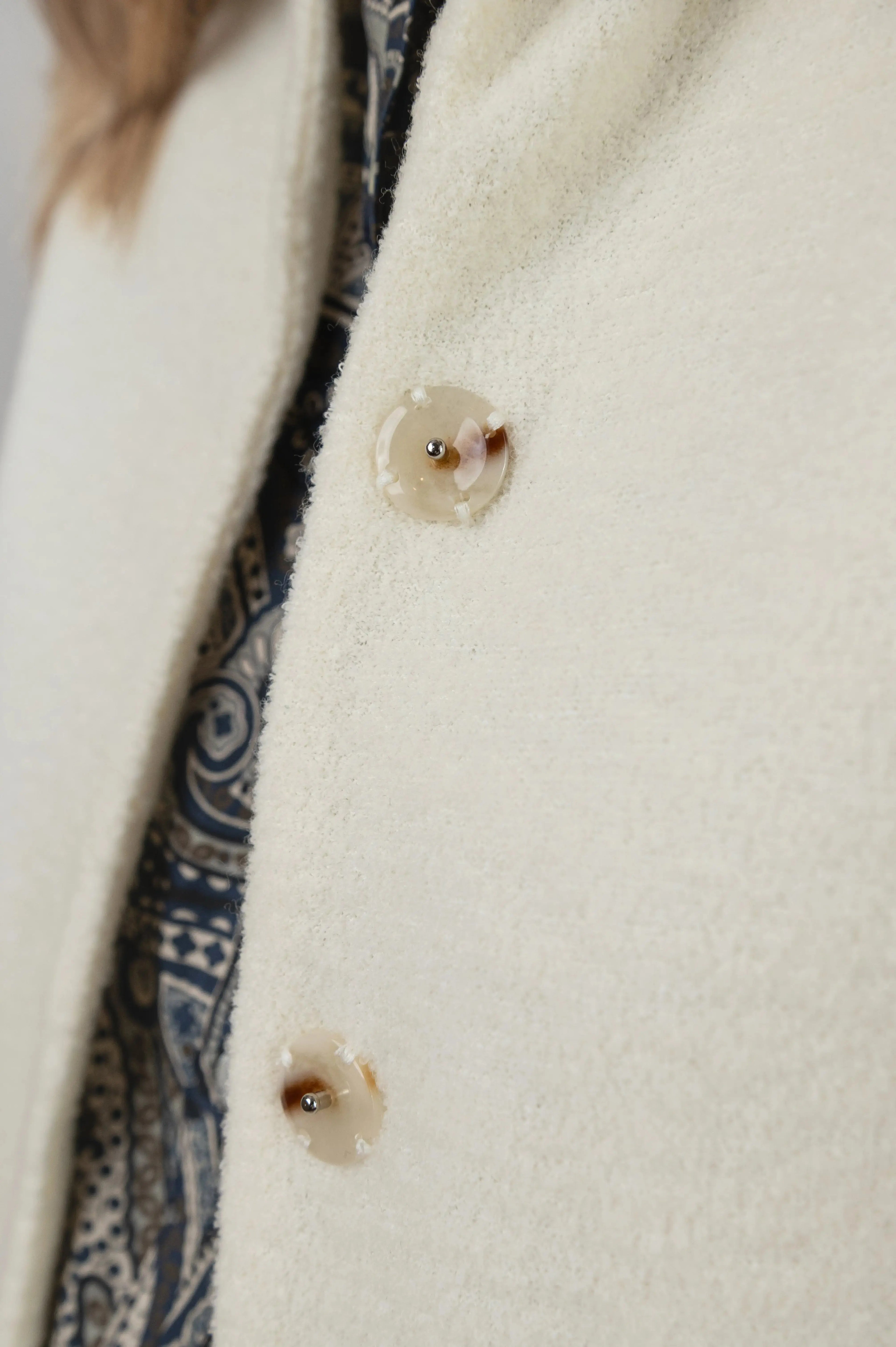 Gilet sans manches Ouessant en jersey de laine couleur crème, détail des boutons effet corne, porté avec une chemise Narcisse en popeline de coton à motif paisley cashmere.