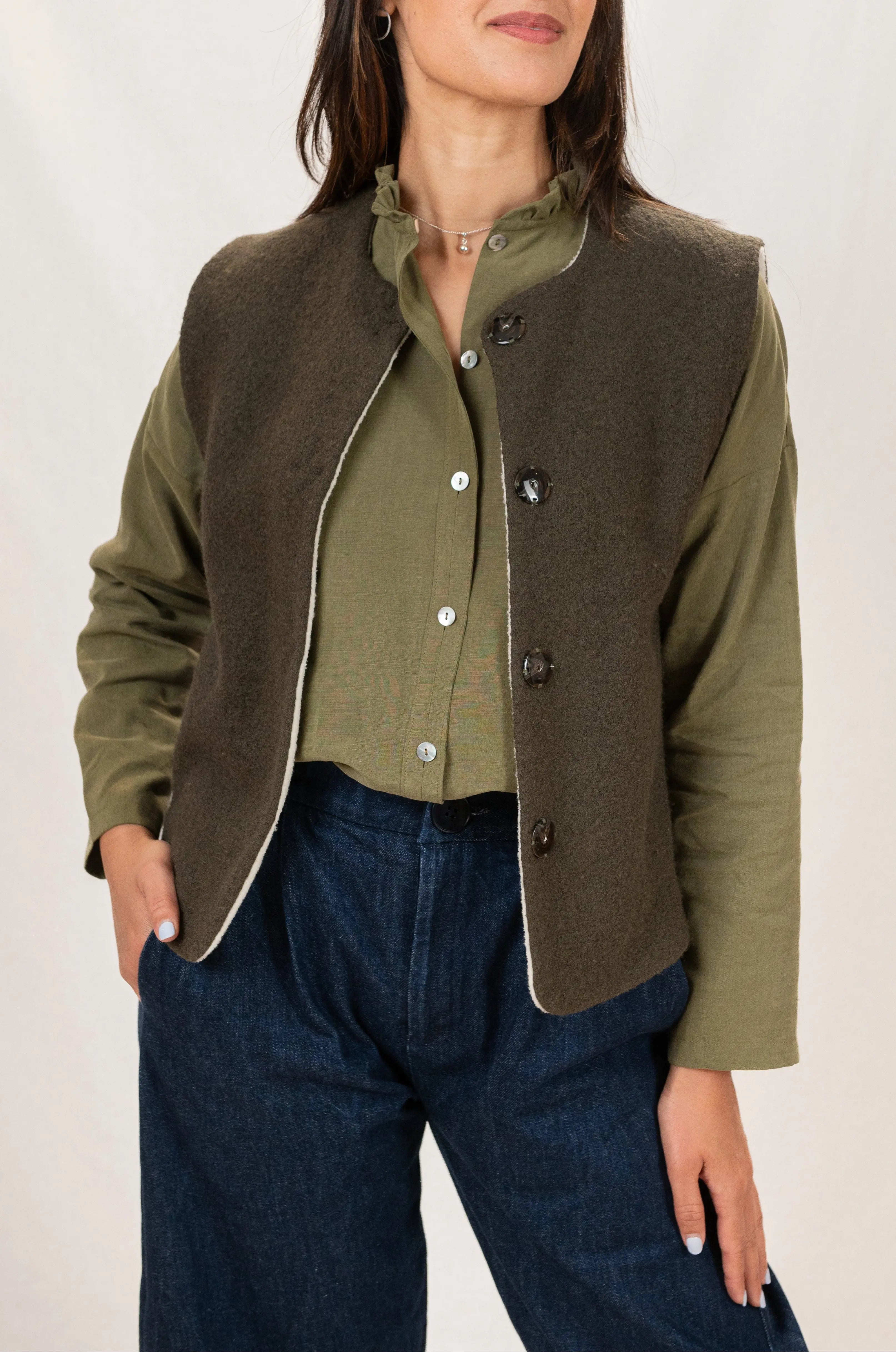 Gilet sans manches Ouessant réversible en laine bouillie vert forêt, vu de face, porté avec une chemise Narcisse en lin et soie couleur kaki et un pantalon Sylène en denim, coupe barrel leg.