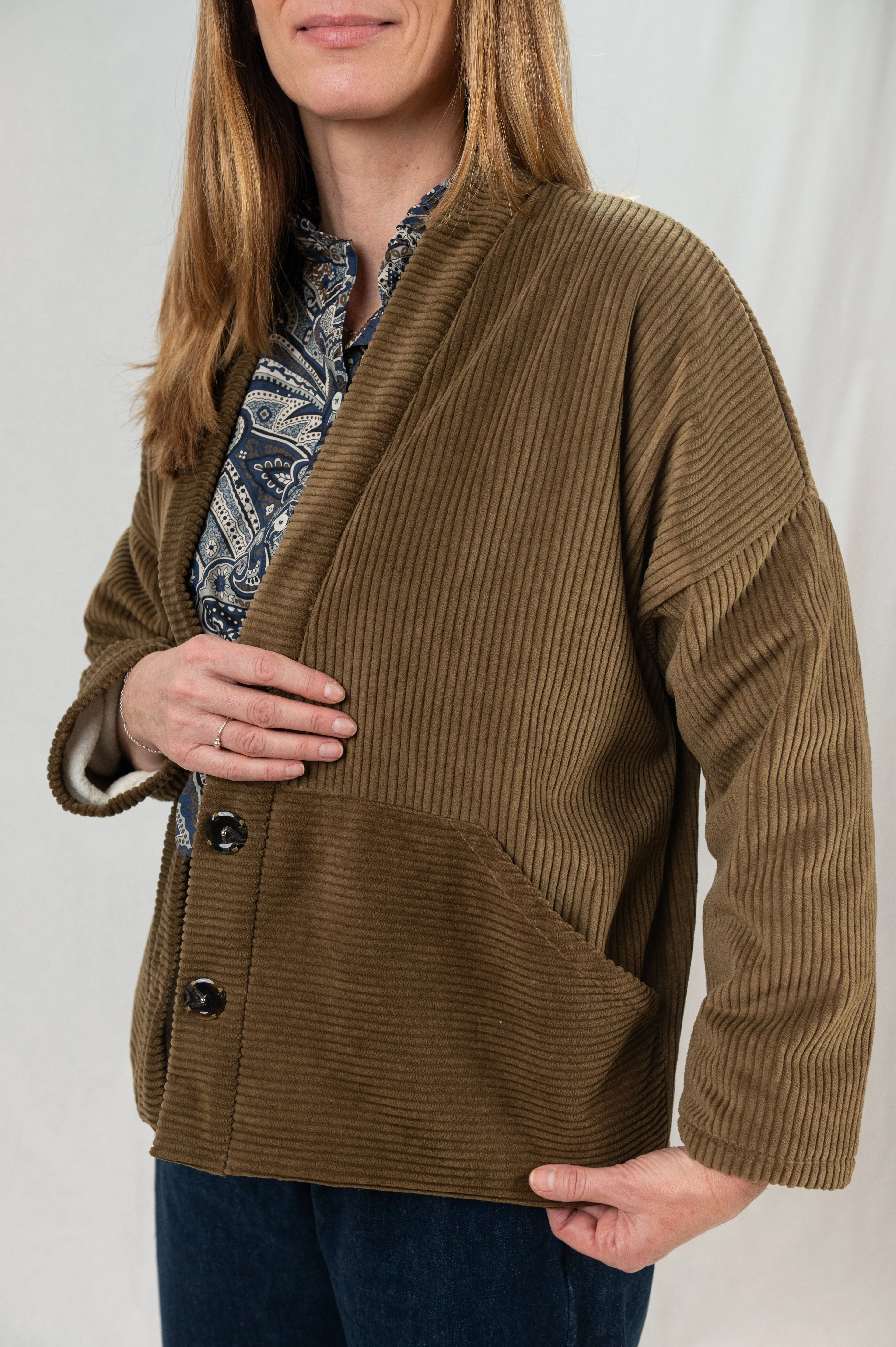 Manteau Cévennes coupe kimono en velours côtelé havane, détail de la poche, porté avec une chemise Narcisse à motif paisley cashmere et un pantalon Sylène en denim, coupe Barrel Leg.
